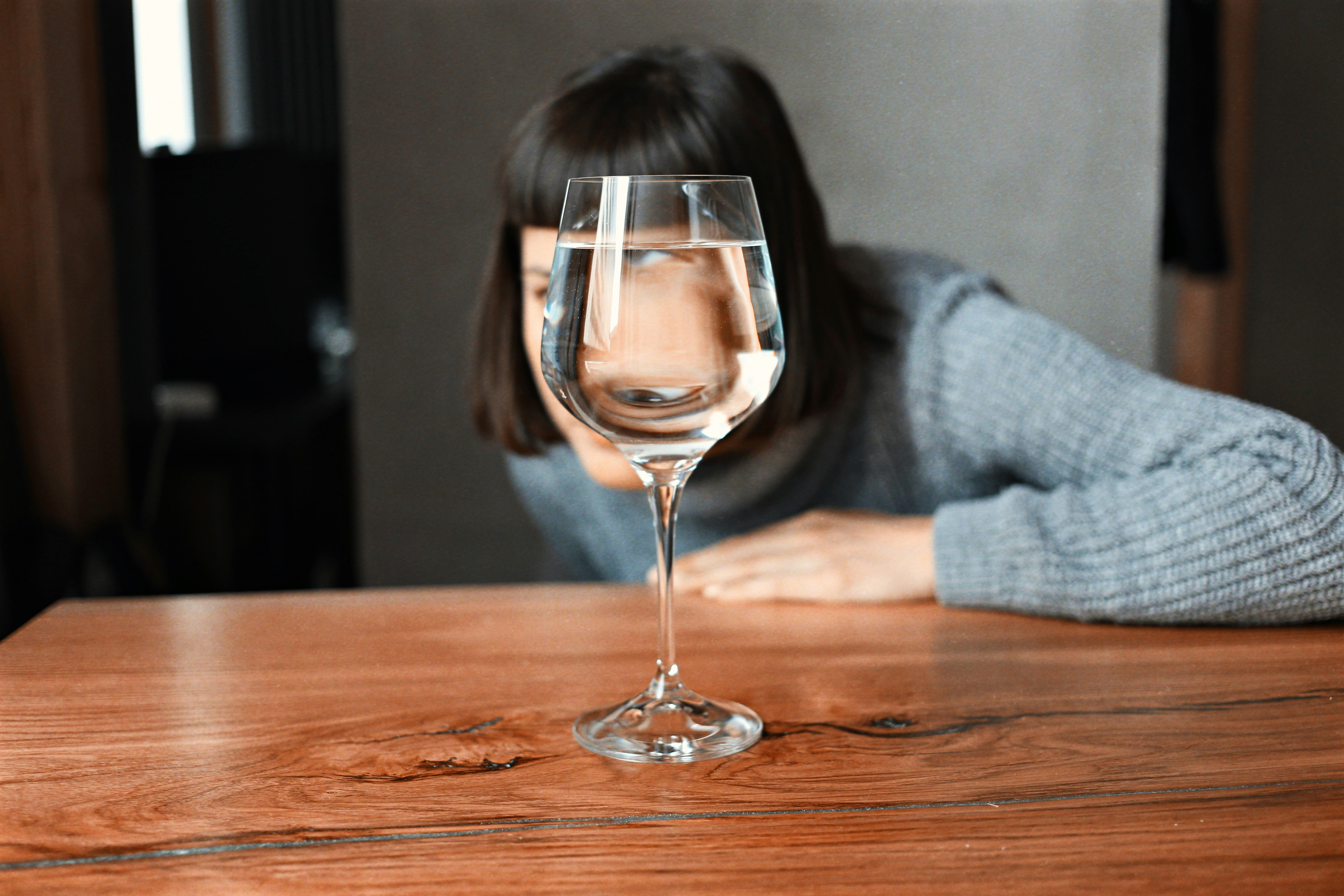 Woman sitting thoughtfully with a glass of wine looking reflective and calm